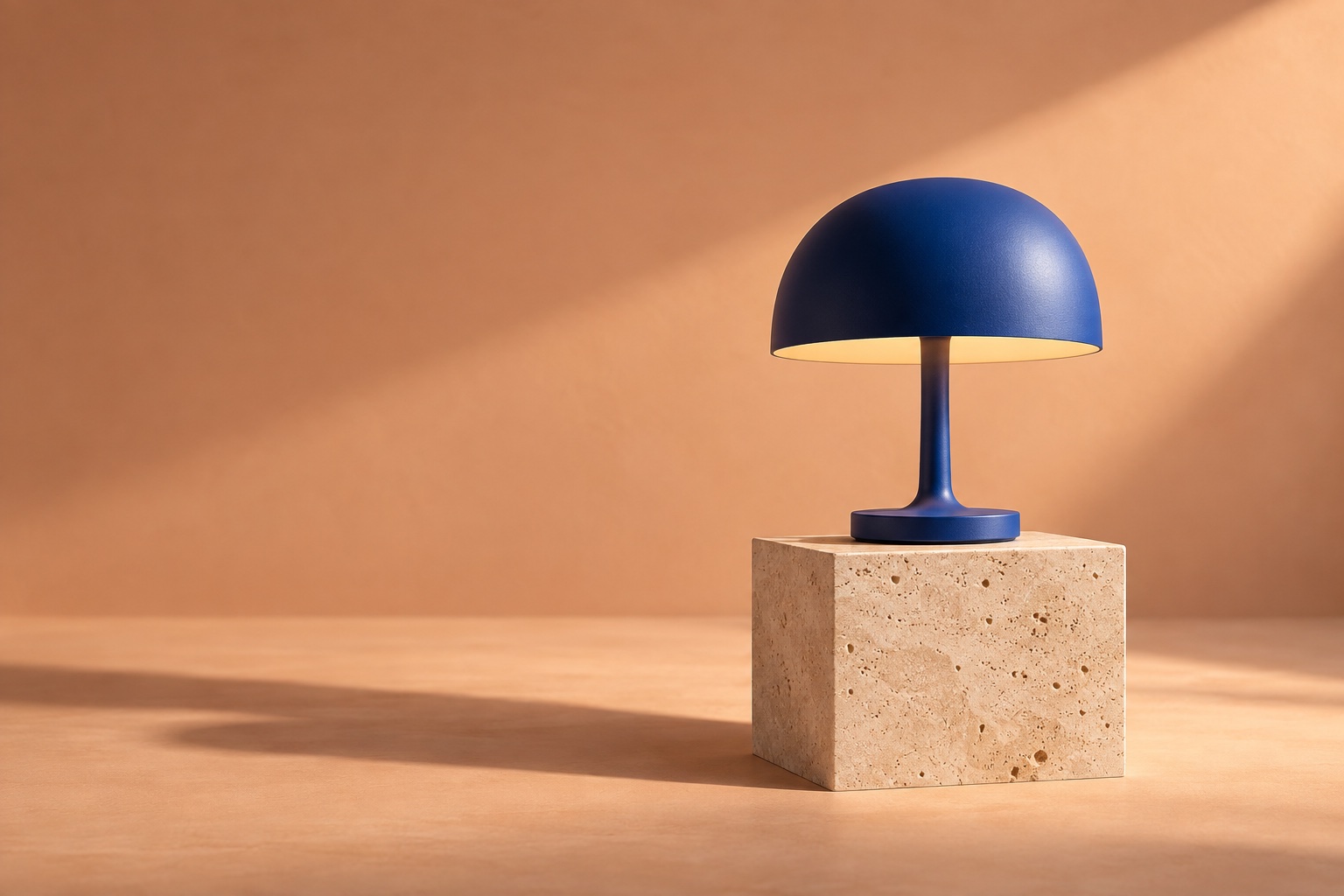 A cobalt-blue lamp casts a warm glow over a limestone plinth in afternoon light.